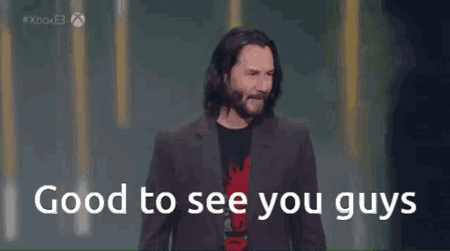 a man in a suit is standing on a stage with the words good to see you guys behind him