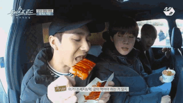 a man in a black jacket is eating a piece of food with korean writing on it