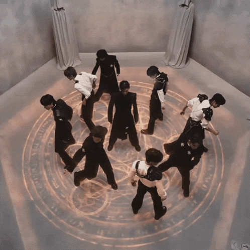 a group of people are dancing in a circle with a glowing circle in the middle