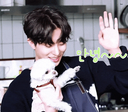 a man holds a small white dog in his arms and says " 안녕 " in green