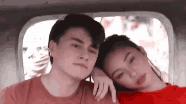 a boy and a girl are sitting next to each other in a car . the girl is wearing a red shirt .