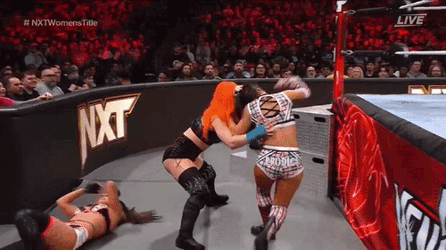 two women are wrestling in a ring with a nxt logo on the wall