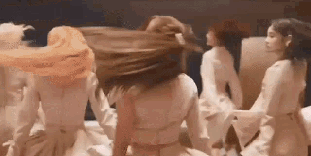 a group of women are dancing together on a bed in a room .