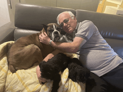 a man is laying on a couch with a dog and two puppies