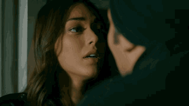 a close up of a woman 's face with a man 's face in the background
