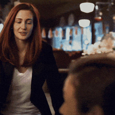 a woman with red hair wearing a black jacket and white shirt