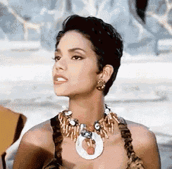 a woman wearing a necklace and earrings is looking to the side