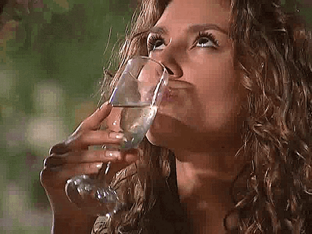 a woman with curly hair is drinking a glass of water
