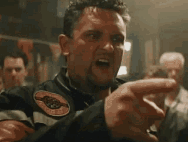 a man in a leather jacket is talking to a group of people in a bar .