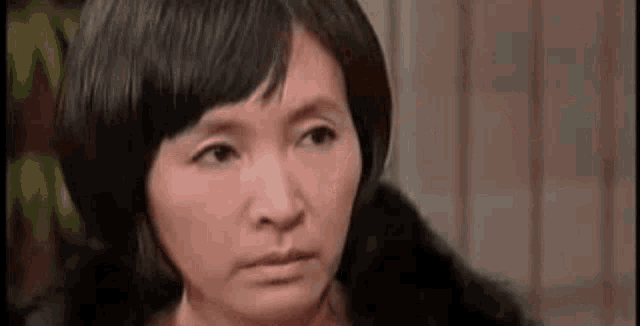 a close up of a woman 's face with short hair and a fur coat .