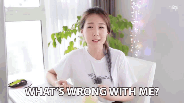 a woman sitting at a desk with the words " what 's wrong with me " on the screen