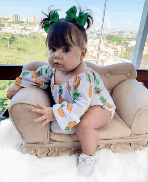 a baby girl wearing a pineapple outfit is sitting on a small chair