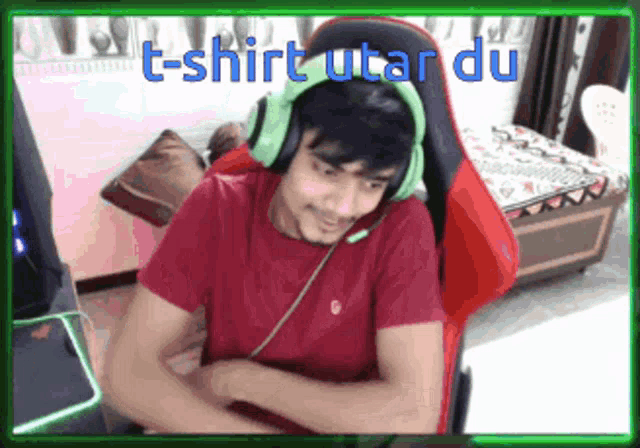 a man wearing headphones and a red shirt is sitting in a chair with the words t-shirt utar du below him