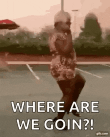 a woman is dancing in a parking lot with the words `` where are we goin '' .