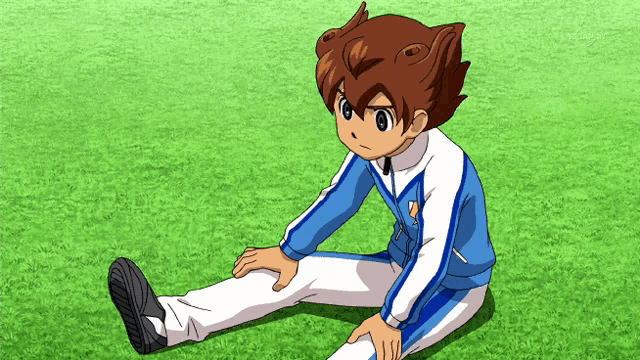 a boy in a blue and white outfit sits on the grass with his legs crossed