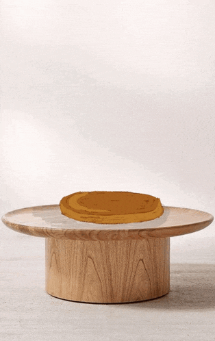 a round wooden table with a pancake on top of it