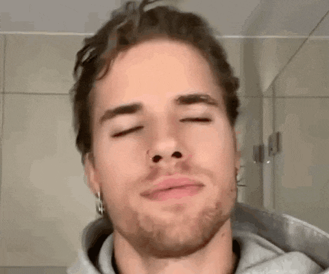 a close up of a man 's face with his eyes closed and a nose ring .