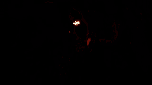 a man is blowing fire from his mouth in the dark