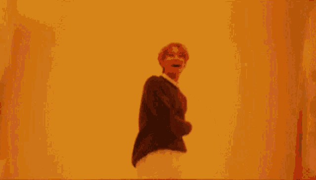 a man is dancing in front of a yellow wall .