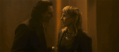 a man and a woman are kissing in front of a wall