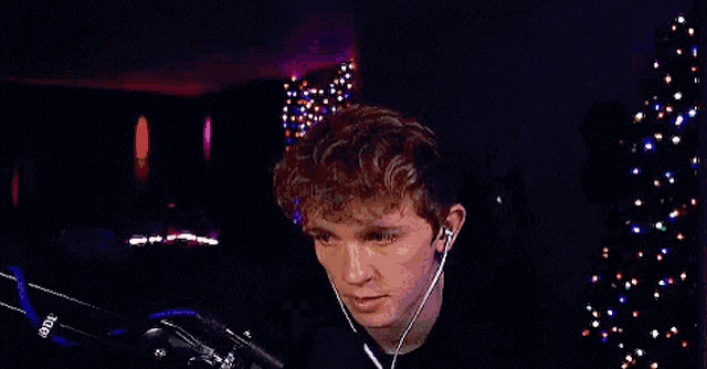 a man wearing headphones is dancing in front of a christmas tree in a dark room .