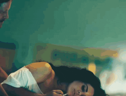 a woman is laying on a bed with a man standing behind her