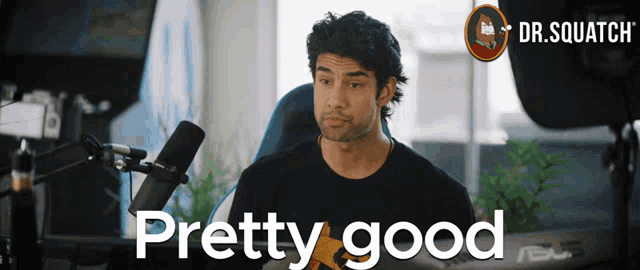 a man sitting in front of a microphone with the words " pretty good " behind him