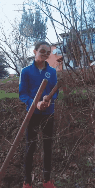 a girl in a blue jacket with a circle on it is holding two wooden sticks