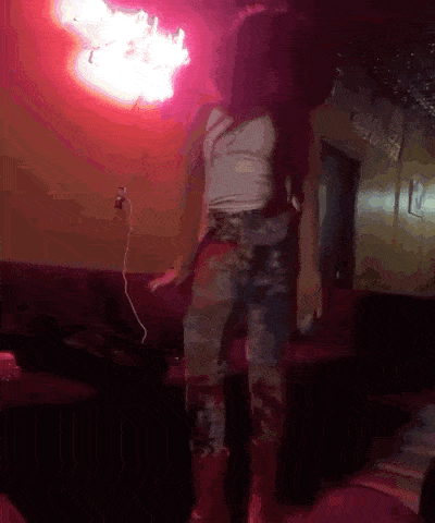 a woman is dancing in a room with a red light behind her