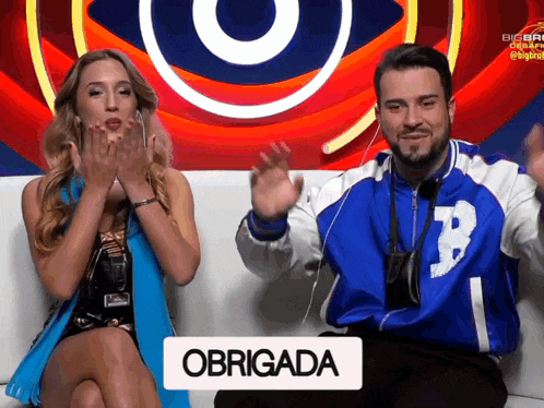 a man and a woman are sitting on a couch with a sign that says obrigada