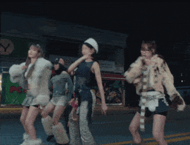a group of girls are dancing on a street in front of a store that says pc