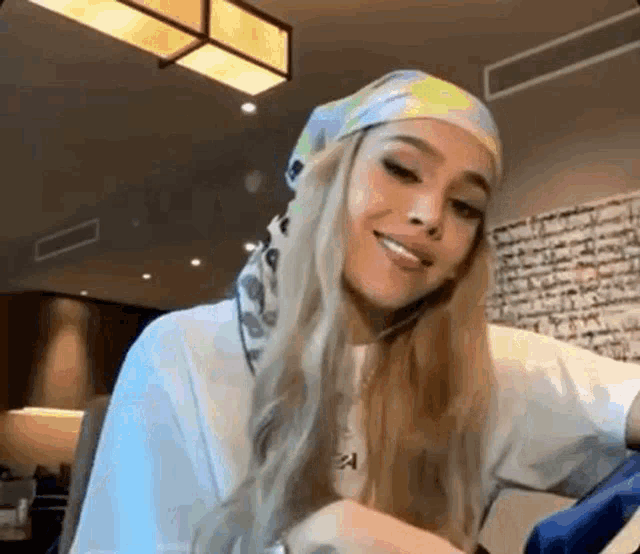 a woman wearing a head scarf and a white shirt is smiling while sitting at a table .
