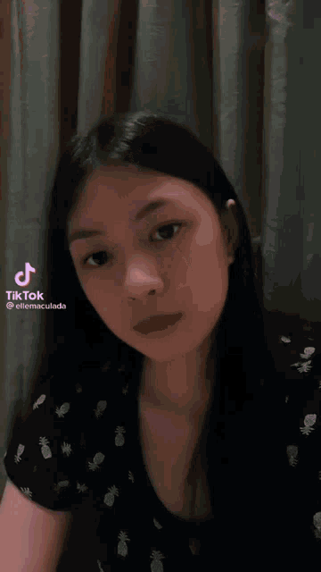 a girl with pineapples on her shirt waves her hand in front of a curtain