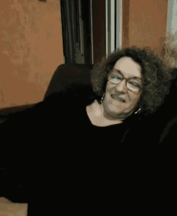 a woman with curly hair and glasses is smiling
