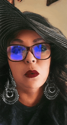 a woman wearing glasses and a black hat has a blue reflection in her glasses