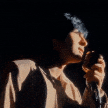 a man singing into a microphone with a shadow behind him