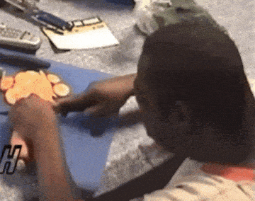 a man is cutting carrots on a blue cutting board with a calculator on the counter