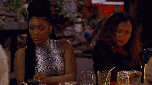 two women are sitting at a table with glasses of water