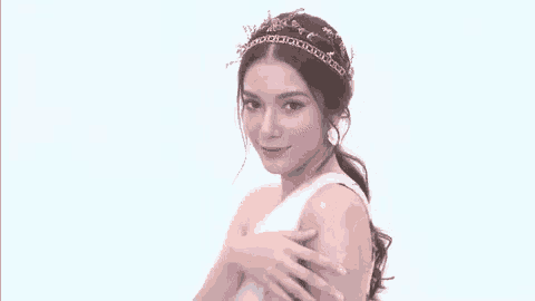 a woman wearing a crown on her head is looking at the camera and smiling .