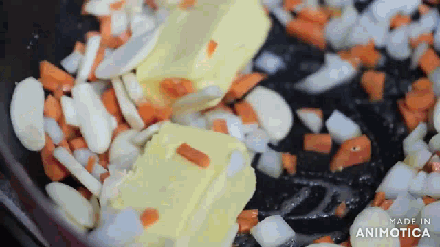 two pieces of butter are being added to a pan of carrots and onions ..