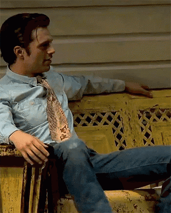 a man in a tie is sitting on a yellow bench .