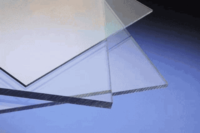 three clear acrylic sheets are stacked on top of each other on a blue surface