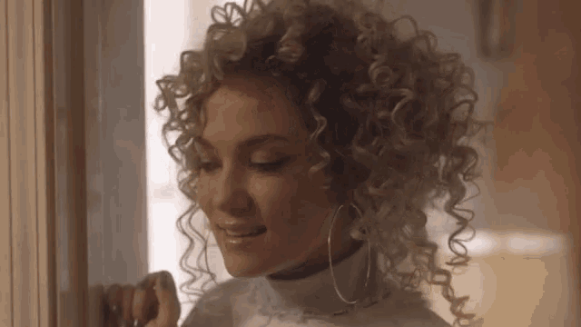 a woman with curly hair and hoop earrings