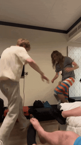 two people are jumping in the air in a bedroom