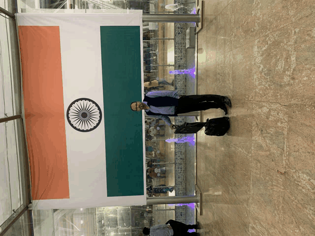 a man in a mask stands in front of a large indian flag