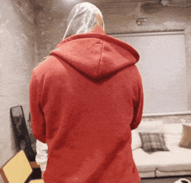 a person wearing a red hoodie is standing in front of a window