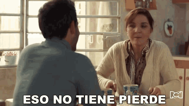 a man and woman sitting at a table with the words eso no tiene pierde written below them
