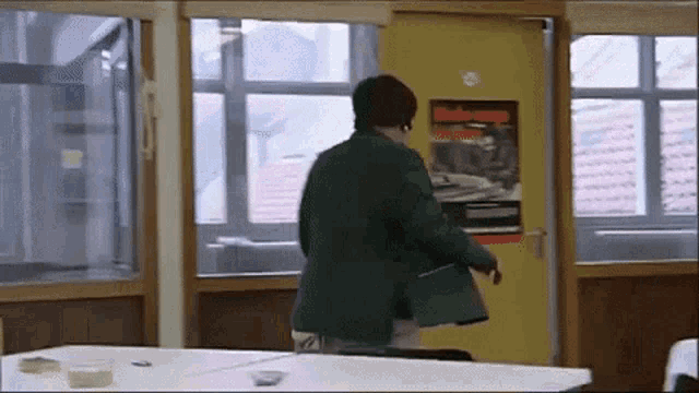 a man in a green jacket is standing in a room