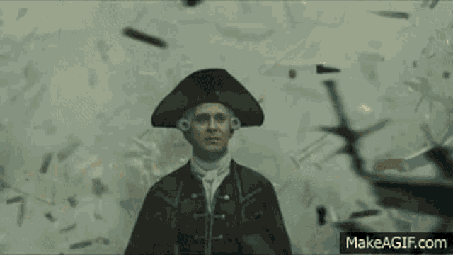 a man in a hat is standing in front of a wall that is being shattered