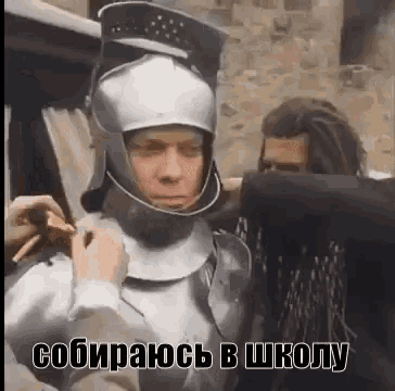 a man in a knight 's helmet is standing next to another man in a black shirt .